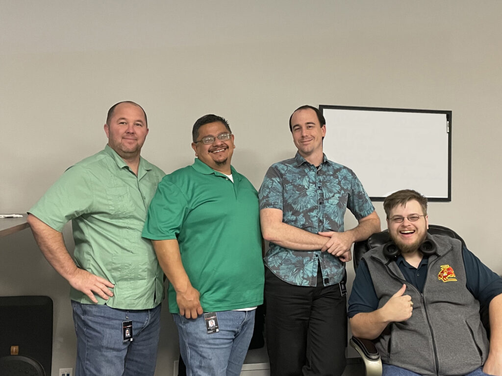 4 men working in technology jobs pose for a picture.