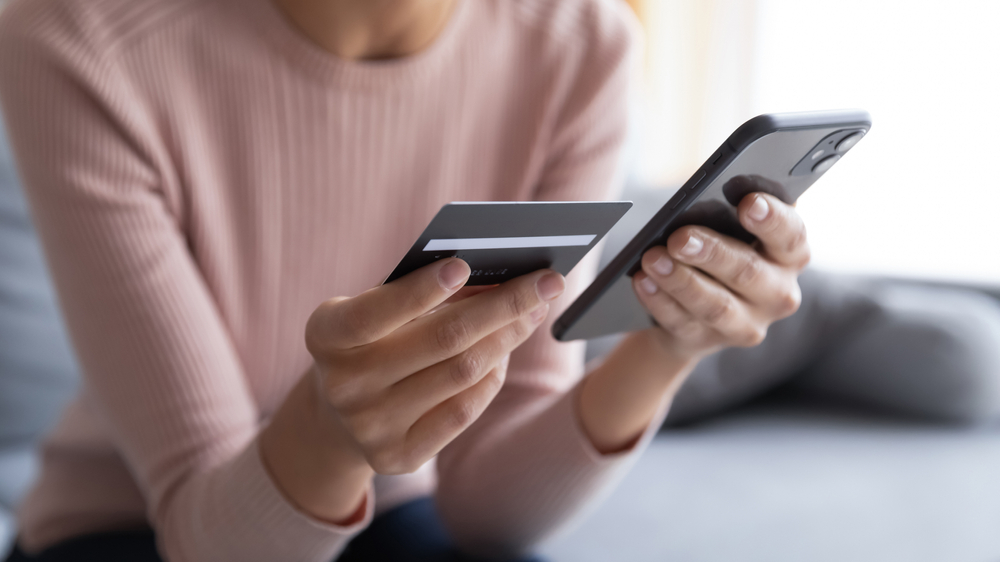 Woman holding credit card and phone, symbolizing an online cybersecurity scam