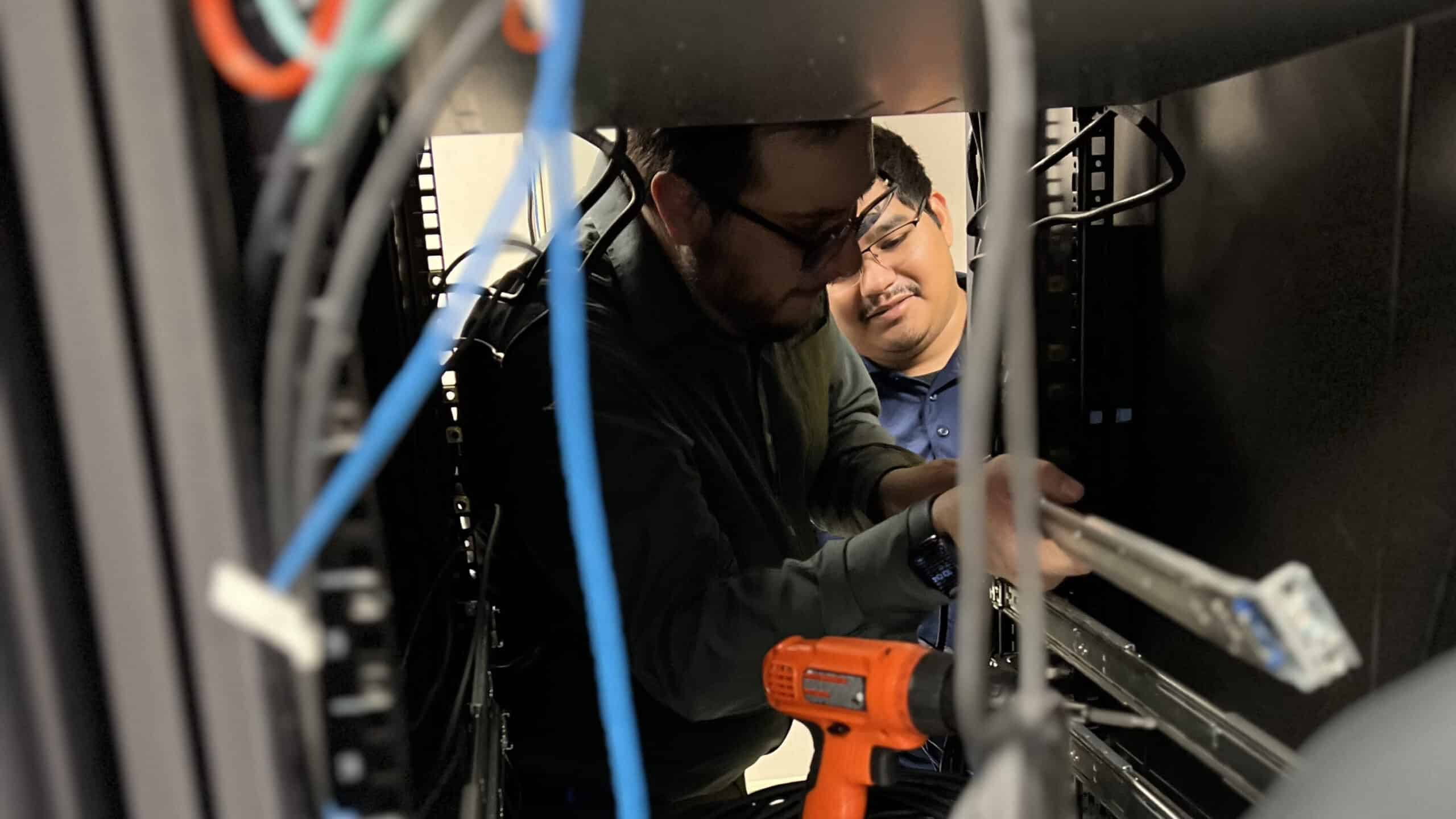 2 men working on an outsourced IT Project in server room